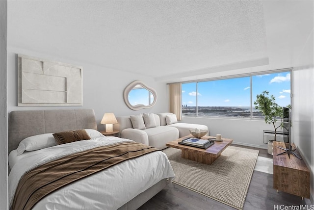 bedroom featuring dark hardwood / wood-style floors, a water view, and a textured ceiling