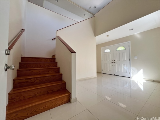 entryway with light tile patterned floors and a high ceiling