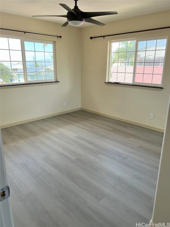 spare room with ceiling fan, a healthy amount of sunlight, and light wood-type flooring