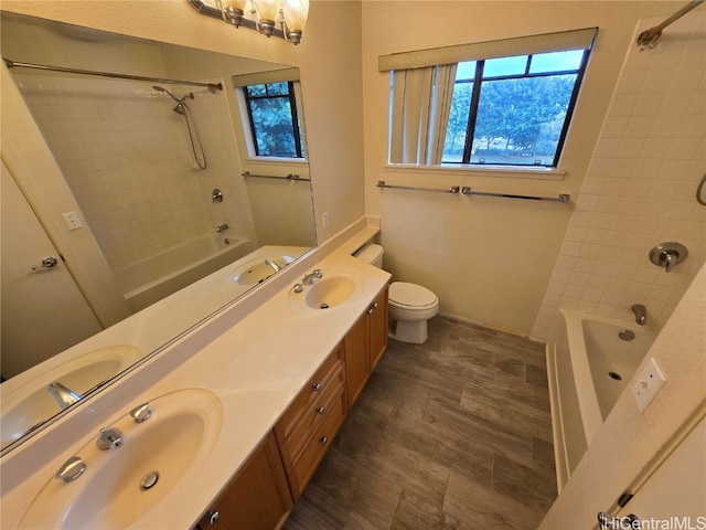 full bathroom with hardwood / wood-style flooring, tiled shower / bath combo, toilet, and vanity