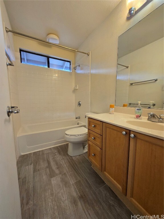 full bathroom featuring toilet, vanity, hardwood / wood-style flooring, and tiled shower / bath combo