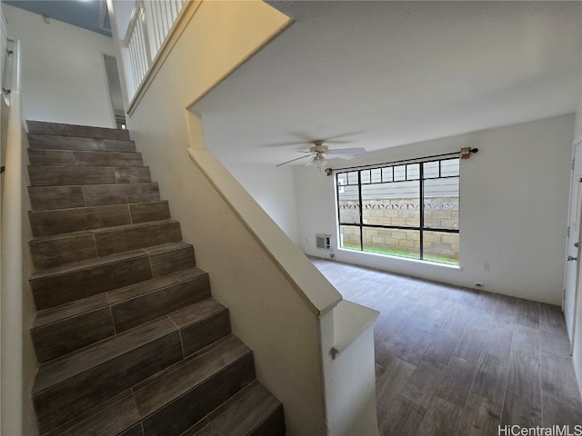 stairway with ceiling fan and wood-type flooring