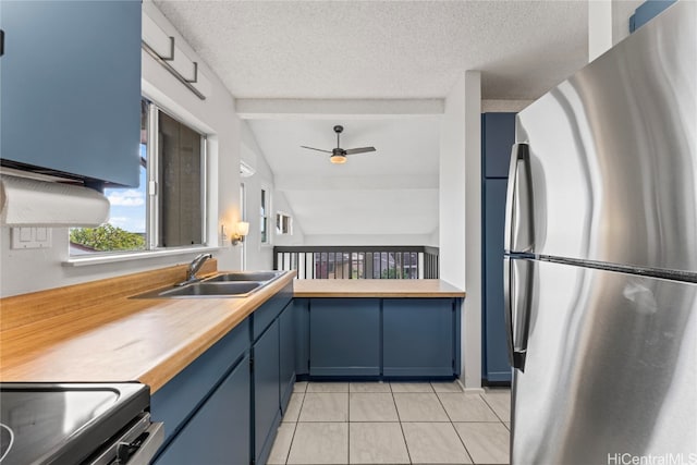 kitchen with wood counters, stainless steel appliances, ceiling fan, sink, and lofted ceiling