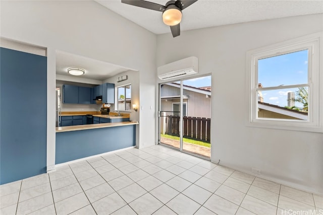 kitchen featuring blue cabinetry, a wall mounted air conditioner, a wealth of natural light, and light tile patterned flooring