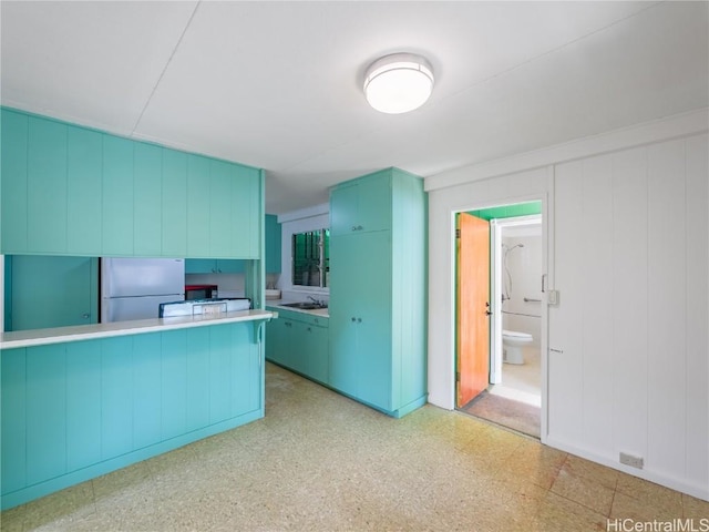 kitchen featuring stainless steel fridge, kitchen peninsula, and sink