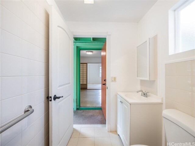 bathroom with vanity, toilet, tile patterned flooring, and tile walls