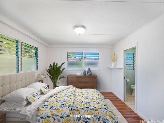 bedroom with hardwood / wood-style flooring and ensuite bath