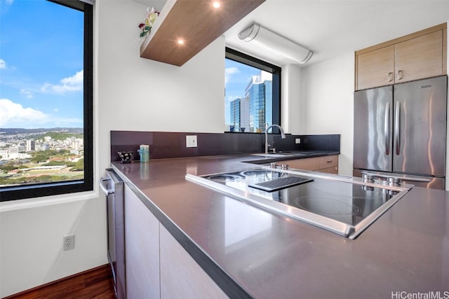 kitchen with a sink, a healthy amount of sunlight, stainless steel fridge, and a city view