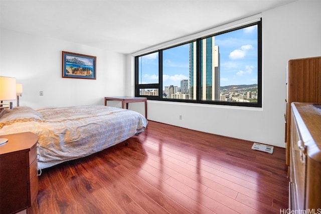 bedroom with wood finished floors and a city view