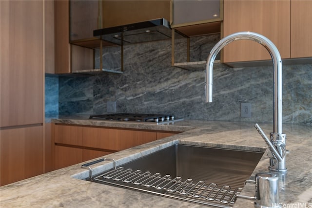 kitchen with sink, ventilation hood, tasteful backsplash, and stainless steel gas stovetop