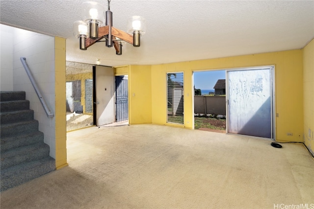 interior space with carpet floors, a textured ceiling, and an inviting chandelier