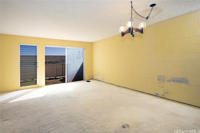 empty room with carpet floors, a textured ceiling, and a chandelier