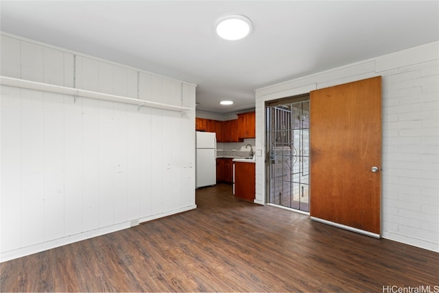 kitchen featuring sink, brick wall, dark hardwood / wood-style floors, and white refrigerator