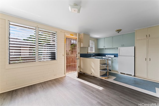 kitchen featuring white appliances, dark wood-type flooring, and brick wall