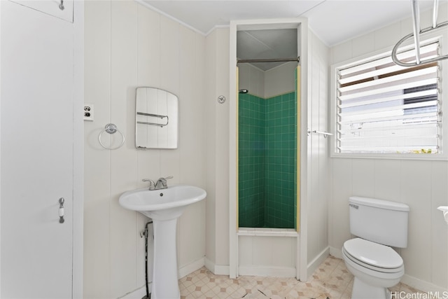 bathroom featuring a tile shower, toilet, ornamental molding, and sink