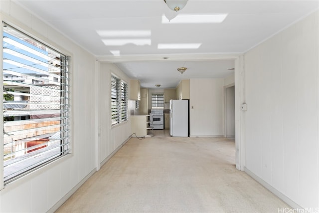 empty room featuring light carpet, crown molding, and a healthy amount of sunlight