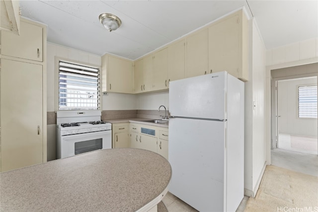 kitchen with light carpet, cream cabinets, white appliances, and sink