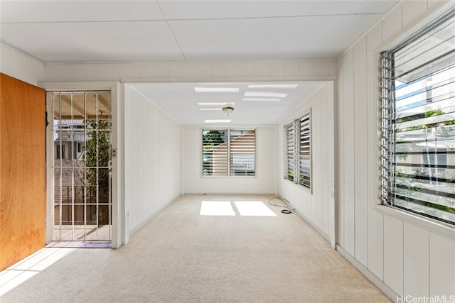 unfurnished room with light carpet and wooden walls