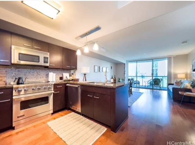 kitchen with kitchen peninsula, stainless steel appliances, light hardwood / wood-style flooring, and floor to ceiling windows