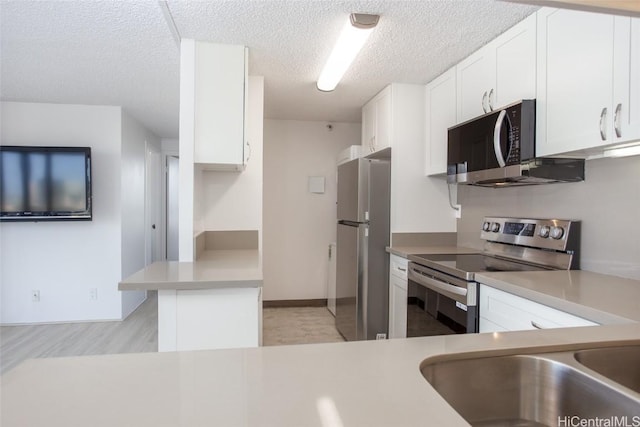 kitchen featuring white cabinets, kitchen peninsula, a textured ceiling, and appliances with stainless steel finishes