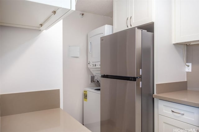 laundry area featuring a textured ceiling and stacked washing maching and dryer