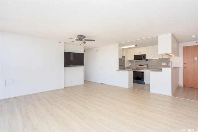 unfurnished living room with ceiling fan, light hardwood / wood-style floors, sink, and a textured ceiling