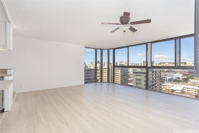 unfurnished living room featuring expansive windows, a healthy amount of sunlight, a textured ceiling, and light wood-type flooring