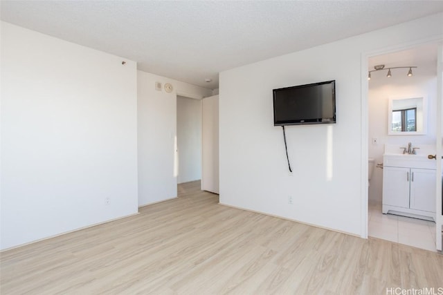 empty room with light hardwood / wood-style flooring, a textured ceiling, and sink