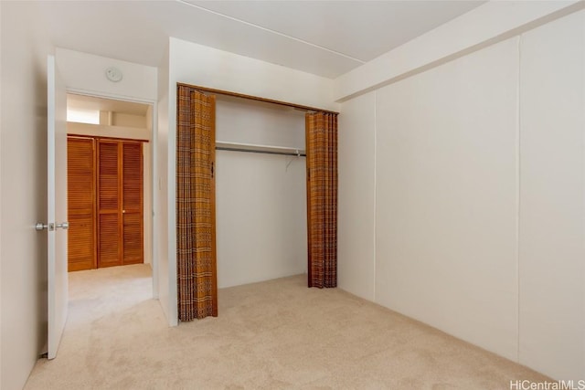 unfurnished bedroom featuring a closet and light colored carpet