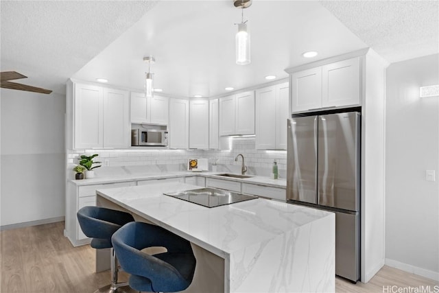 kitchen featuring pendant lighting, a center island, sink, appliances with stainless steel finishes, and white cabinetry