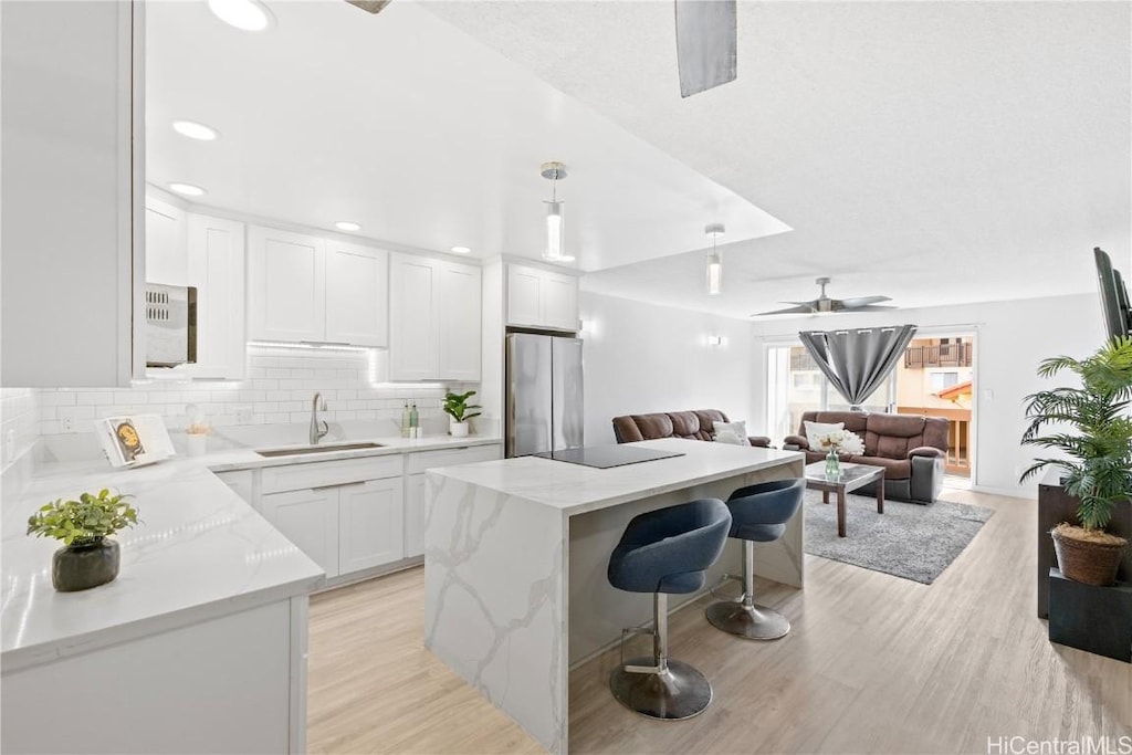 kitchen featuring stainless steel fridge, light hardwood / wood-style flooring, white cabinetry, and sink