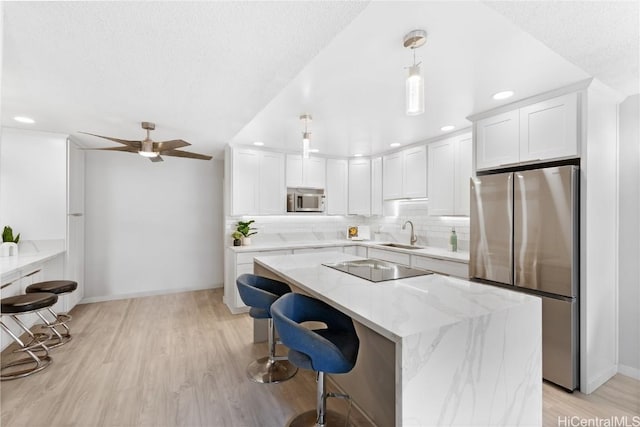 kitchen featuring white cabinets, decorative light fixtures, light stone counters, and appliances with stainless steel finishes