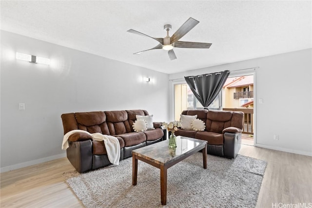 living room featuring ceiling fan, a textured ceiling, and light wood-type flooring