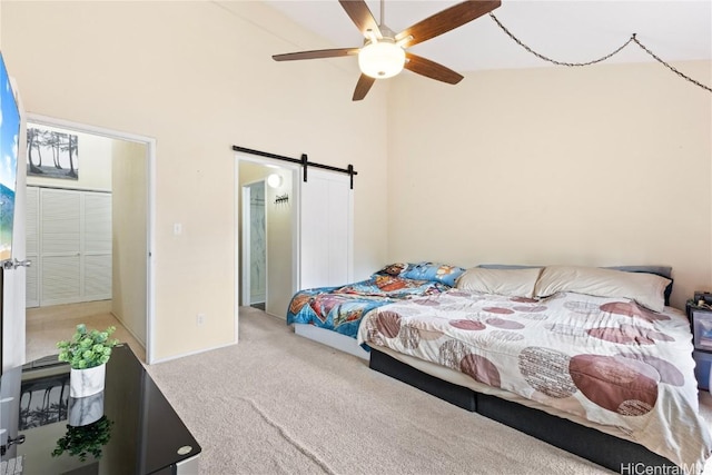 carpeted bedroom with ceiling fan and a barn door