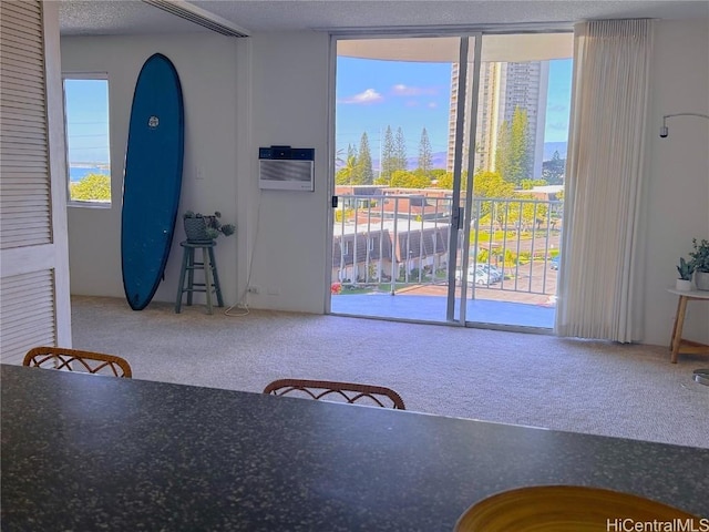 unfurnished dining area featuring carpet, plenty of natural light, a wall mounted air conditioner, and a textured ceiling