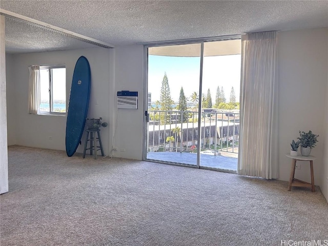 carpeted spare room with a wall mounted air conditioner and a textured ceiling