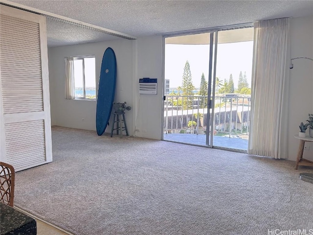 carpeted empty room with a wall mounted air conditioner and a textured ceiling