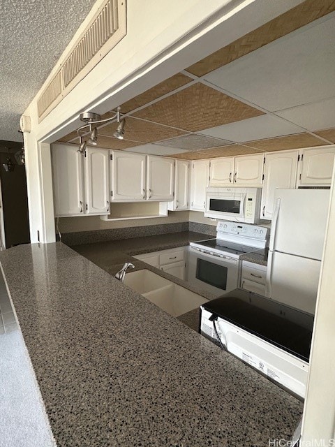 kitchen featuring white cabinetry, sink, white appliances, and kitchen peninsula