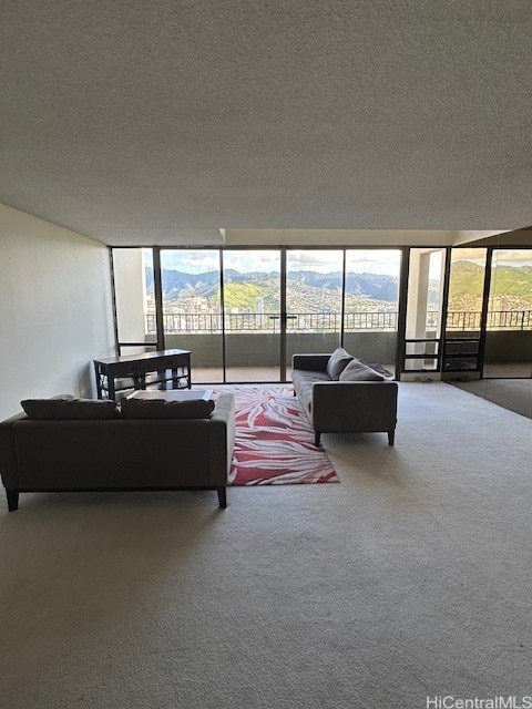 living room featuring carpet, a mountain view, a textured ceiling, and a wall of windows