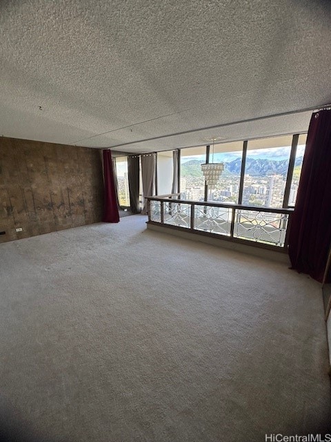 carpeted spare room featuring a textured ceiling and wood walls