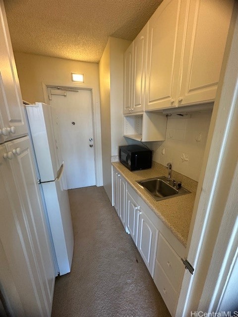 kitchen with white cabinets, white refrigerator, carpet floors, and sink