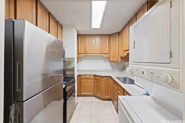 kitchen featuring electric range, stainless steel fridge, light tile patterned flooring, and stacked washer / dryer