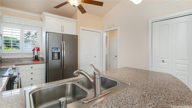 kitchen with stone counters, white cabinetry, sink, stainless steel appliances, and vaulted ceiling