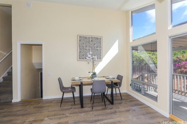 dining space featuring a towering ceiling and dark wood-type flooring