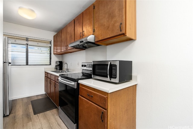 kitchen featuring stainless steel appliances, extractor fan, dark hardwood / wood-style floors, and sink