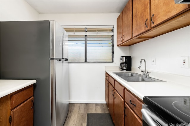 kitchen featuring stainless steel fridge, sink, and light hardwood / wood-style floors