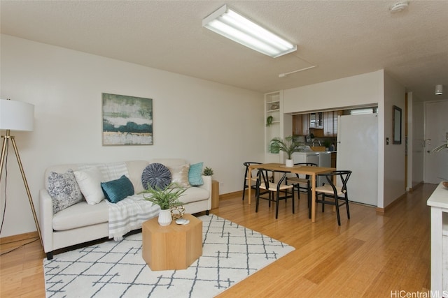 living room featuring light wood-type flooring and a textured ceiling