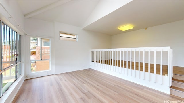 empty room featuring lofted ceiling with beams and light hardwood / wood-style floors