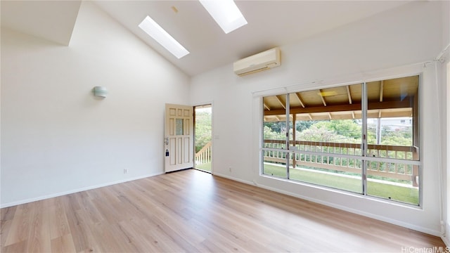 empty room featuring high vaulted ceiling, a healthy amount of sunlight, light hardwood / wood-style floors, and a wall unit AC