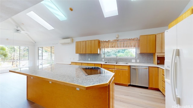 kitchen featuring white fridge with ice dispenser, sink, stainless steel dishwasher, vaulted ceiling with skylight, and a kitchen island